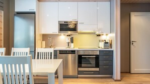 A compact kitchen with white cabinets, stainless steel appliances, and a wooden floor.