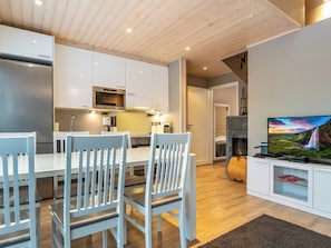 Ett modernt kök med vita skåp, en inbyggd ugn och en matplats med två vita stolar.