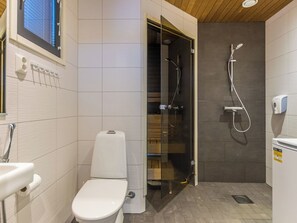 Een moderne badkamer met toilet, een glazen douchecabine en een wastafel.