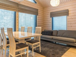 Een modern interieur met een eettafel, stoelen, een bank en grote ramen.