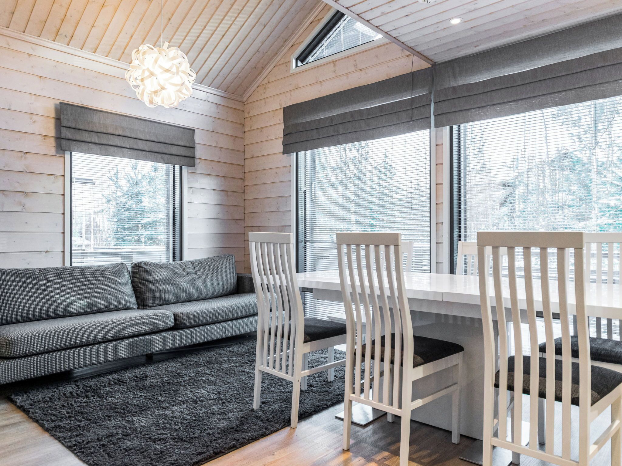 Un intérieur moderne avec un plafond en bois, un canapé, des fauteuils et une table à manger.