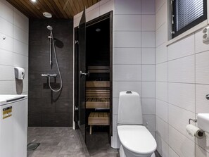 A modern bathroom with a shower, toilet, and a small wooden bench.