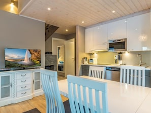 A modern kitchen with white cabinets, a dining table, and chairs.