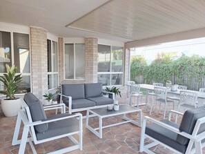 An outdoor patio with white furniture, including a sofa and chairs, and a table. - Golden Beach Escape | Walk to Beach & Pumicestone Passage (Sunshine Coast)