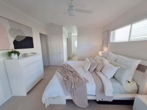 Un dormitorio con cama, cómoda, ventilador de techo y ventana con persianas.