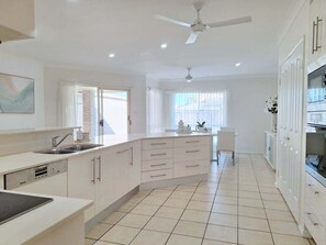 Una cocina moderna con una isla central, electrodomésticos integrados y un ventilador de techo.