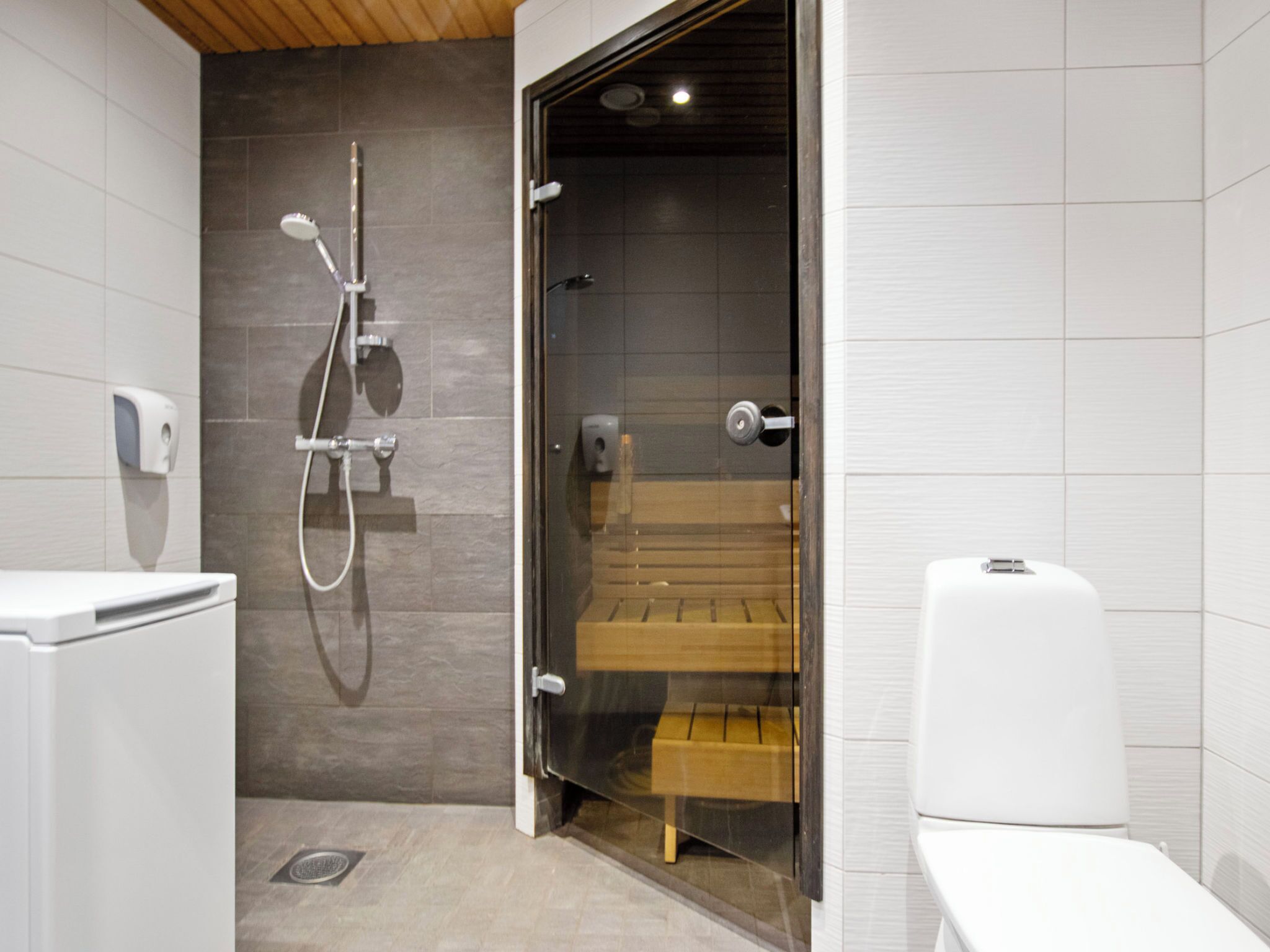 Une salle de bain moderne équipée d’une douche, de toilettes et d’un banc.