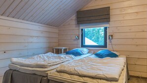 Ein Cabin-Zimmer mit zwei Betten, einem kleinen Tisch und einem Fenster mit Blick auf Bäume.