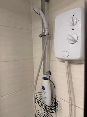 Eine Dusche mit Duschbrause, einer Bedienkonsole zur Steuerung von Temperatur und Druck sowie einer Flasche Nivea Creme Soft Seife.