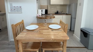 A compact kitchen with a dining table, chairs, and a trash bin. - Cosy studio in Finsbury Park, 18 minutes from Central London (London)