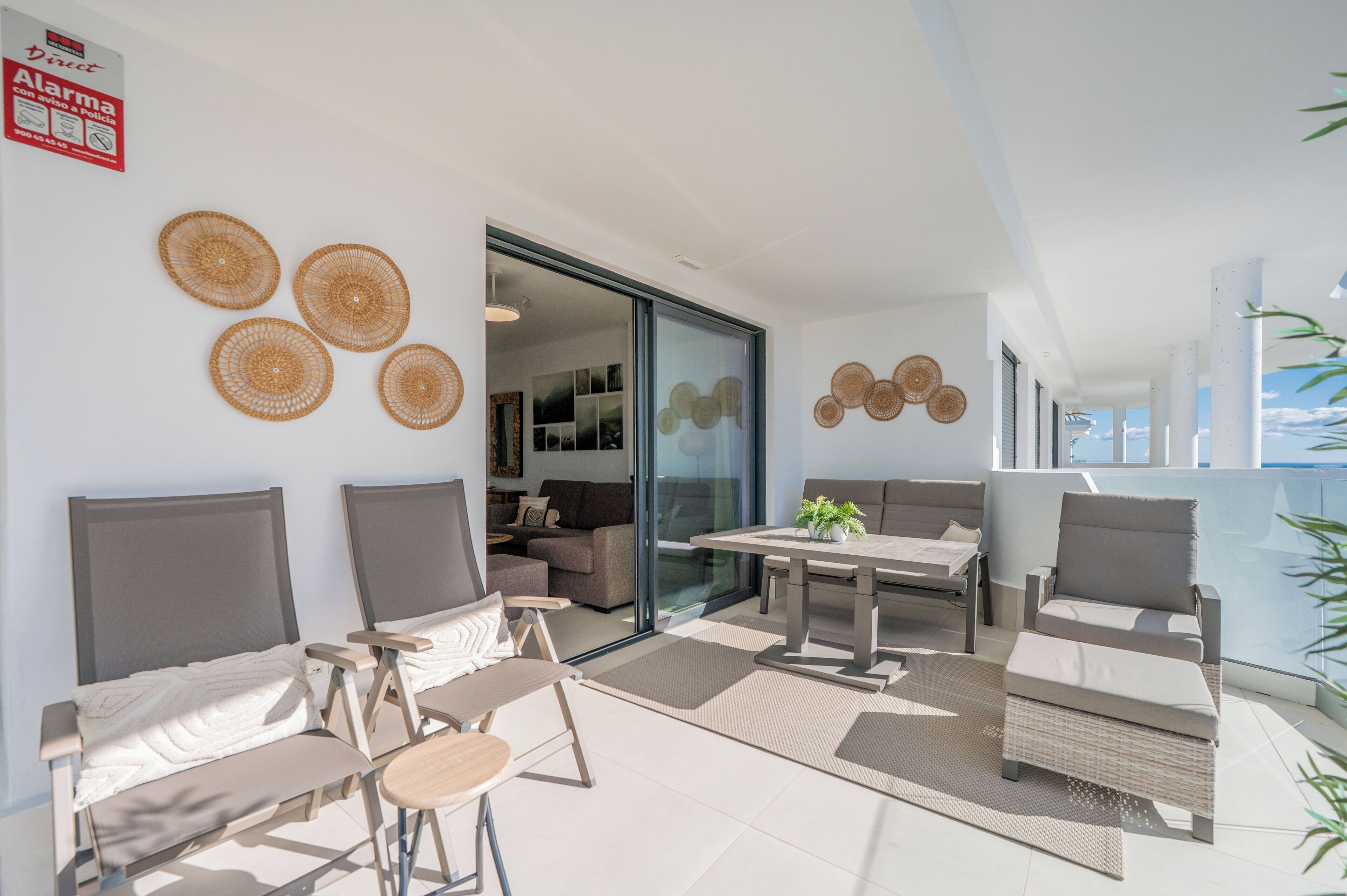 A modern living area with a sofa, chairs, a table, and a balcony with a view.