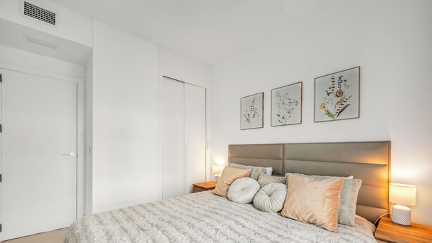 Ein Schlafzimmer mit Bett, Nachttischen, einer Kopfteil und Wandbildern.