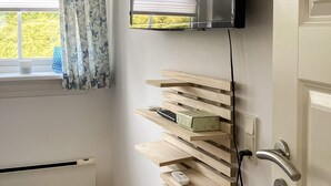 Quarto com estante de madeira embutida, televisão fixada na parede e porta com puxador moderno.