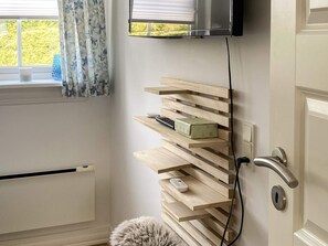 A room with a built-in wooden shelf unit, a television mounted on the wall, and a door with a modern handle. - 4 Star Holiday Home in Vejby (Vejby)