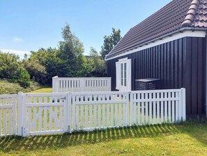 A fenced outdoor area with a building that has a dark exterior and a tiled roof. - 4 Star Holiday Home in Vejby (Vejby)