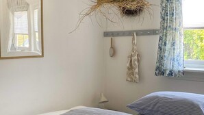 Quarto com duas camas, uma rede suspensa, um espelho e uma janela com cortinas.