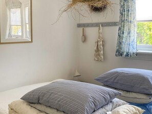 A bedroom with two beds, a hanging nest, a mirror, and a window with curtains. - 4 Star Holiday Home in Vejby (Vejby)