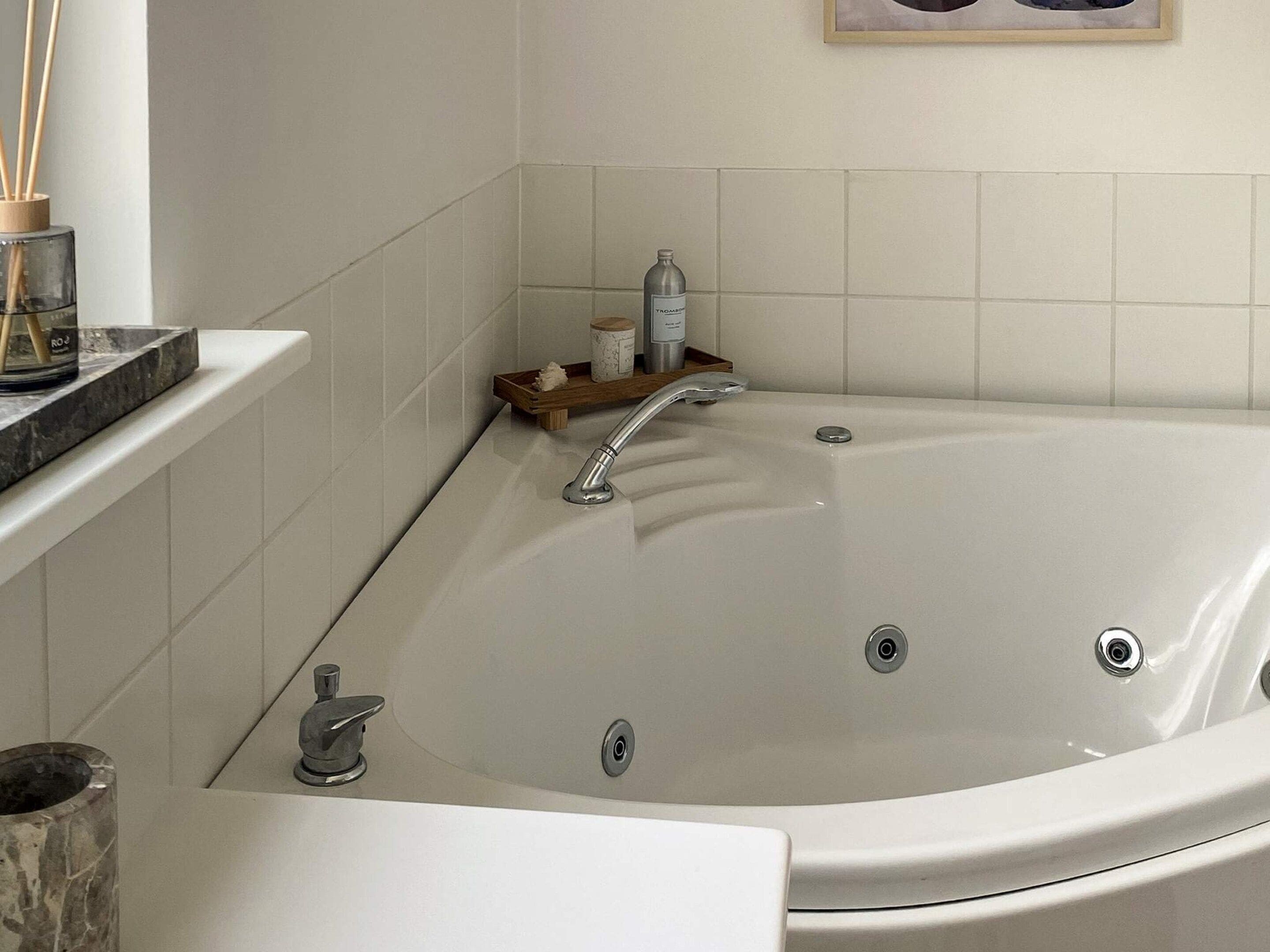 A modern bathroom with a freestanding bathtub, a vanity with a sink, and a shelf with toiletries.
