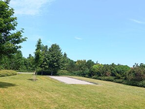 A grassy area with a sand trap and trees. - 4 Star Holiday Home in Vejby (Vejby)
