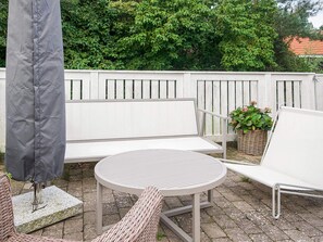 An outdoor patio with a round table, two white chairs, a bench, and a wicker chair. - 4 Star Holiday Home in Vejby (Vejby)