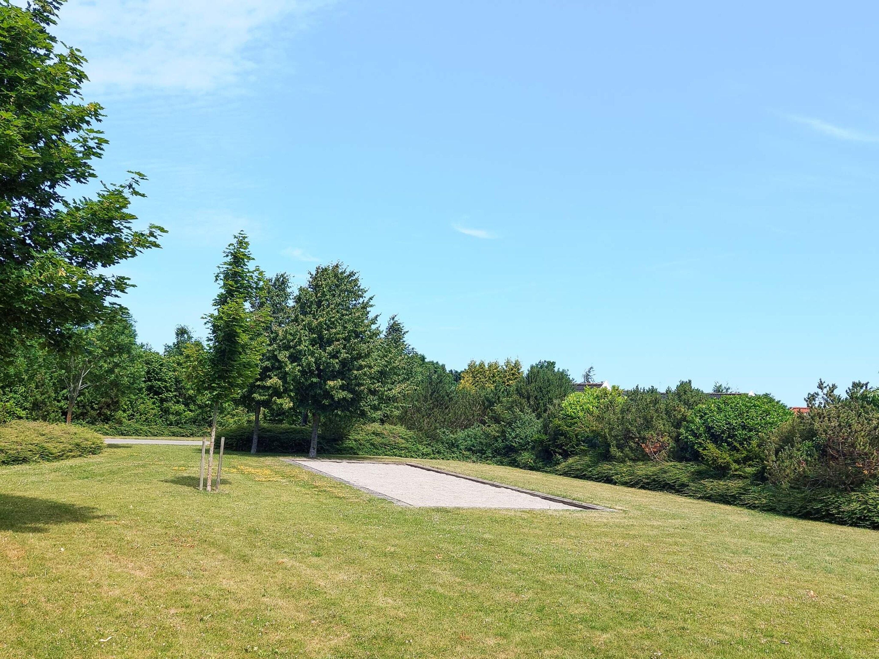 Golfkenttä, jossa on hiekkabunkkeri ja puita.