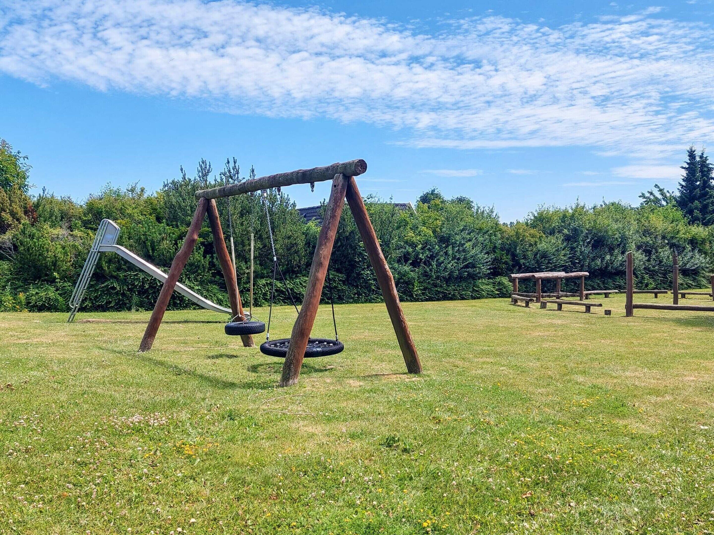 A playground with a swing set and a slide in a grassy field.