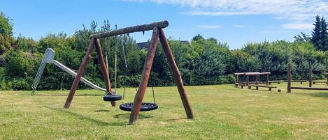 A playground with a swing set and a slide in a grassy field.