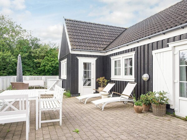 A patio with white furniture, including a table and chairs, and two lounge chairs. - 4 Star Holiday Home in Vejby (Vejby)