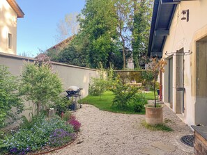 Ein Garten mit Grill, verschiedenen Pflanzen und einem Kiesweg.