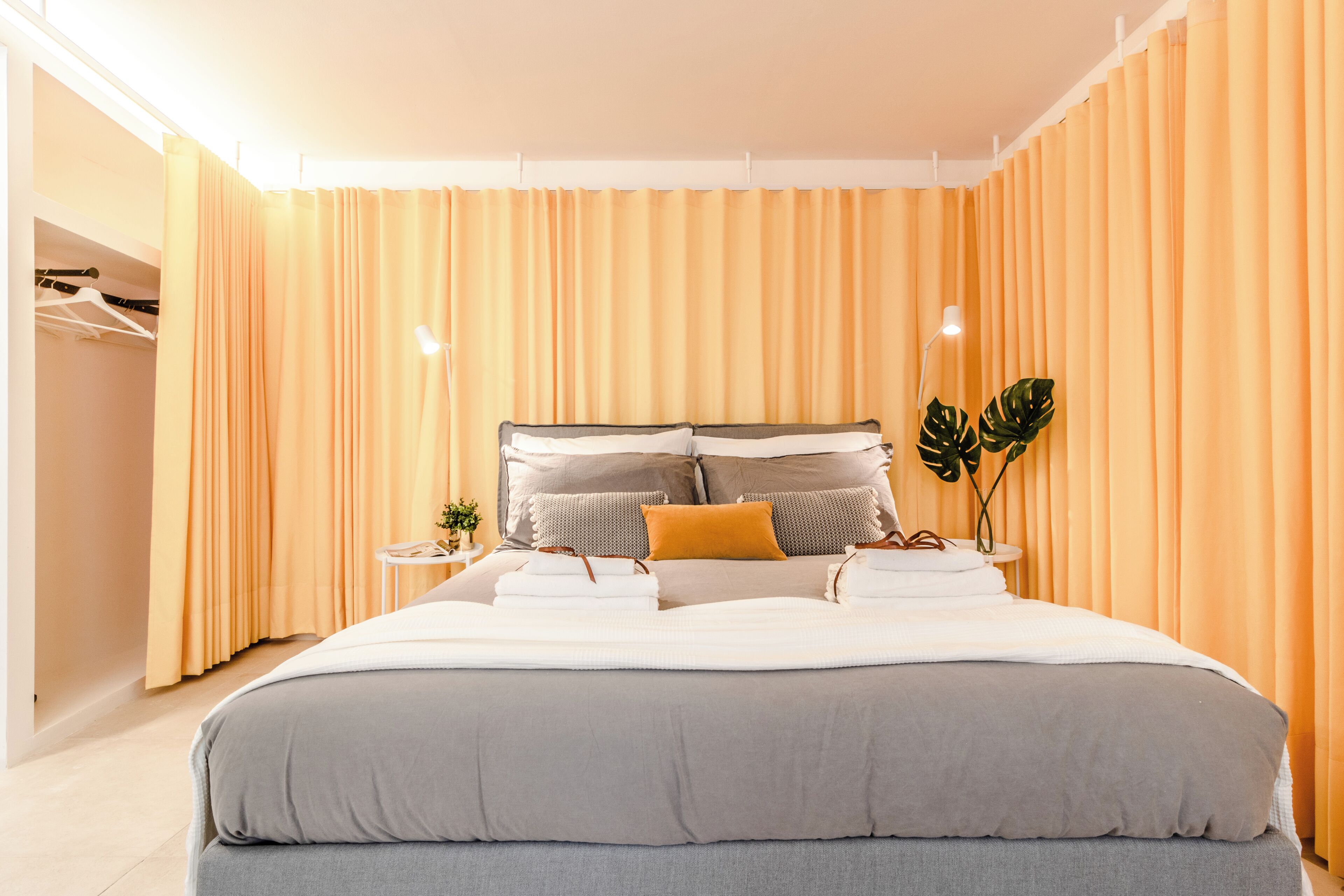 A modern bedroom with a large bed, a bedside table with a lamp, and a wardrobe.
