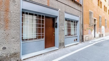 Un edificio con dos grandes puertas tipo garaje, una puerta de madera y una ventana con reja de metal.