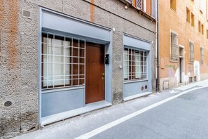 A building with two large garage-style doors, a wooden door, and a window with a metal grid. - HouSmart Arienti 38a (Bologna)