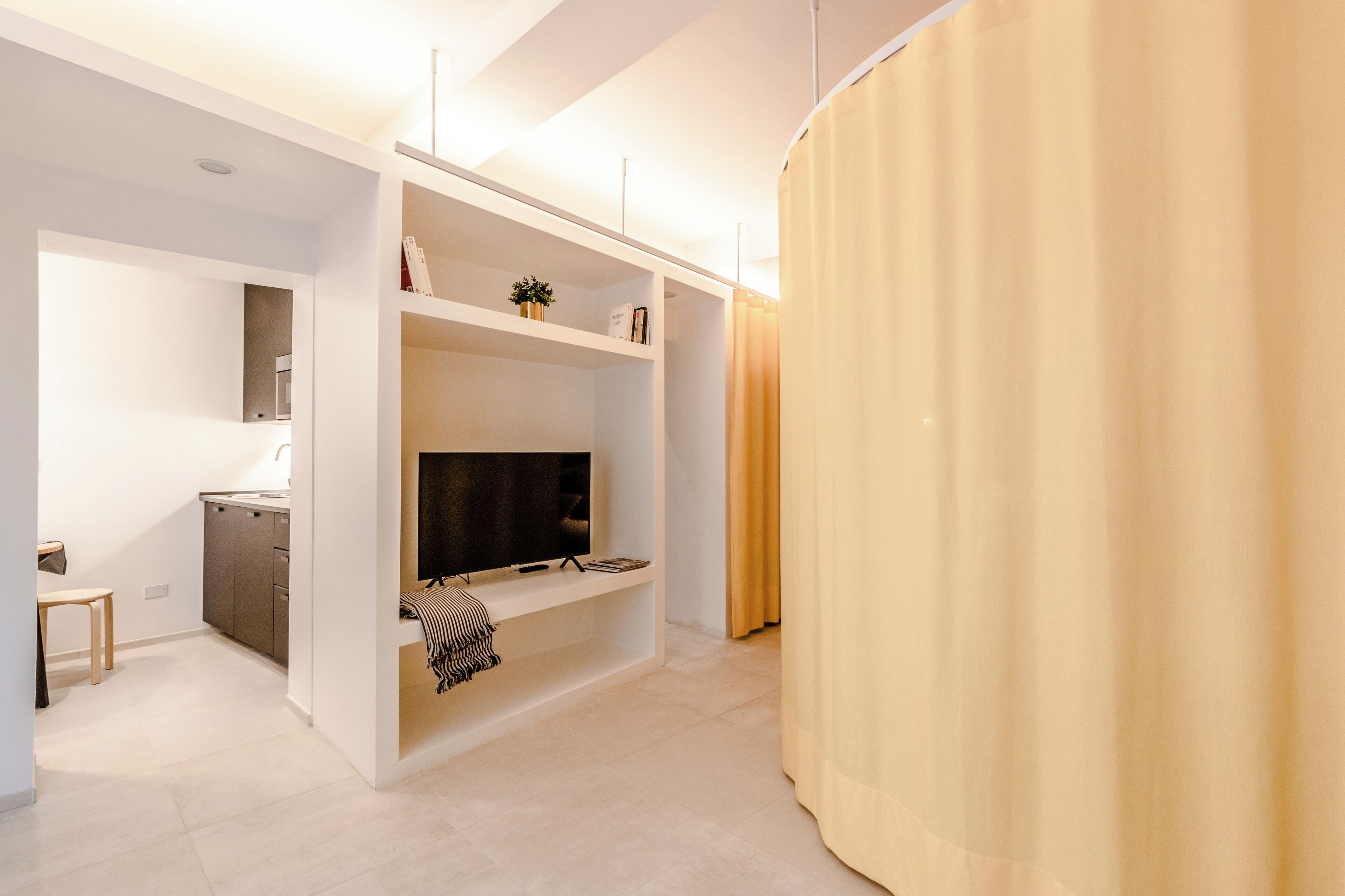 Een modern interieur met een ingebouwde televisie, een klein bureau en een zithoek.