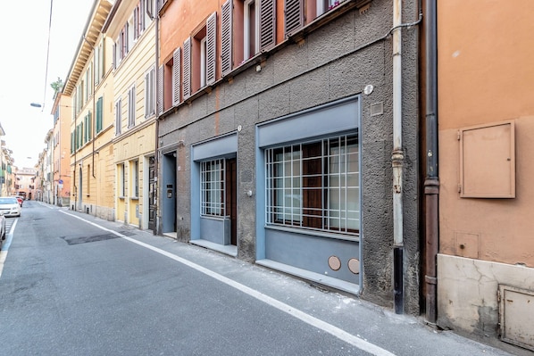 A street view with buildings, a sidewalk, and parked cars.