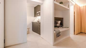A modern interior with a kitchen area, a seating area with a TV, and a separate sleeping area.
