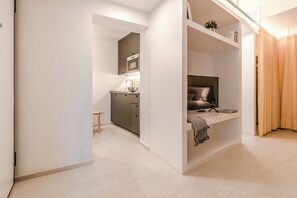 A modern interior with a kitchen area, a seating area with a TV, and a separate sleeping area. - HouSmart Arienti 38a (Bologna)
