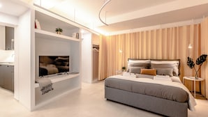 Une chambre moderne avec un grand lit, un téléviseur intégré et un dressing.