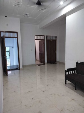 Amplia habitación con piso de mármol, un banco de madera oscura y dos puertas con detalles decorativos.