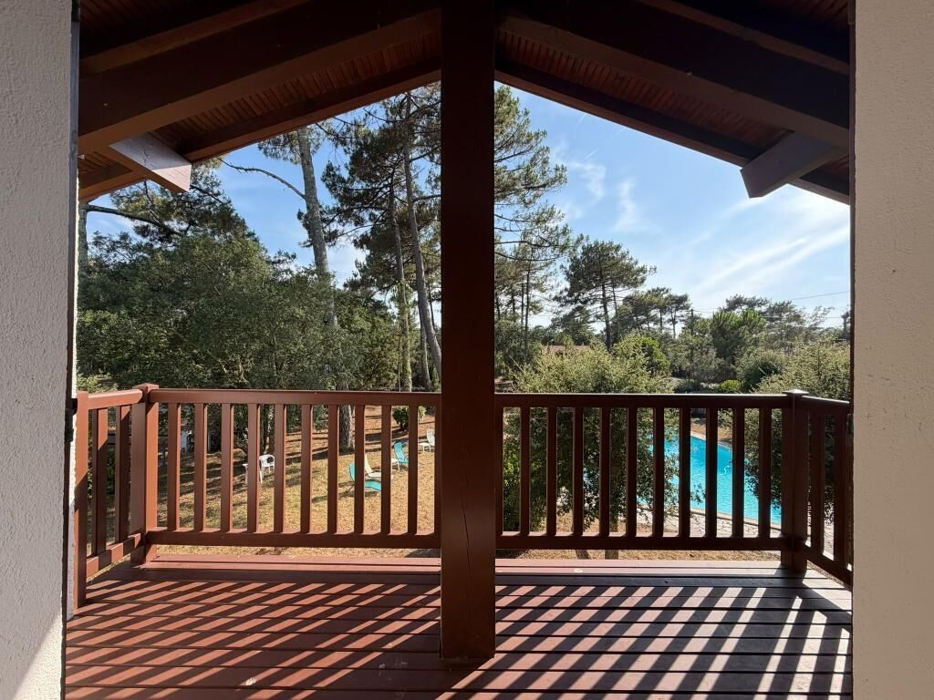 A covered outdoor area with a wooden deck and a view of a swimming pool.
