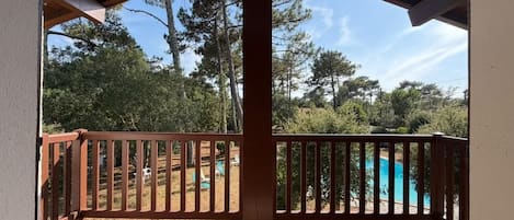Ein überdachter Außenbereich mit Holzterrasse und Blick auf einen Swimmingpool.