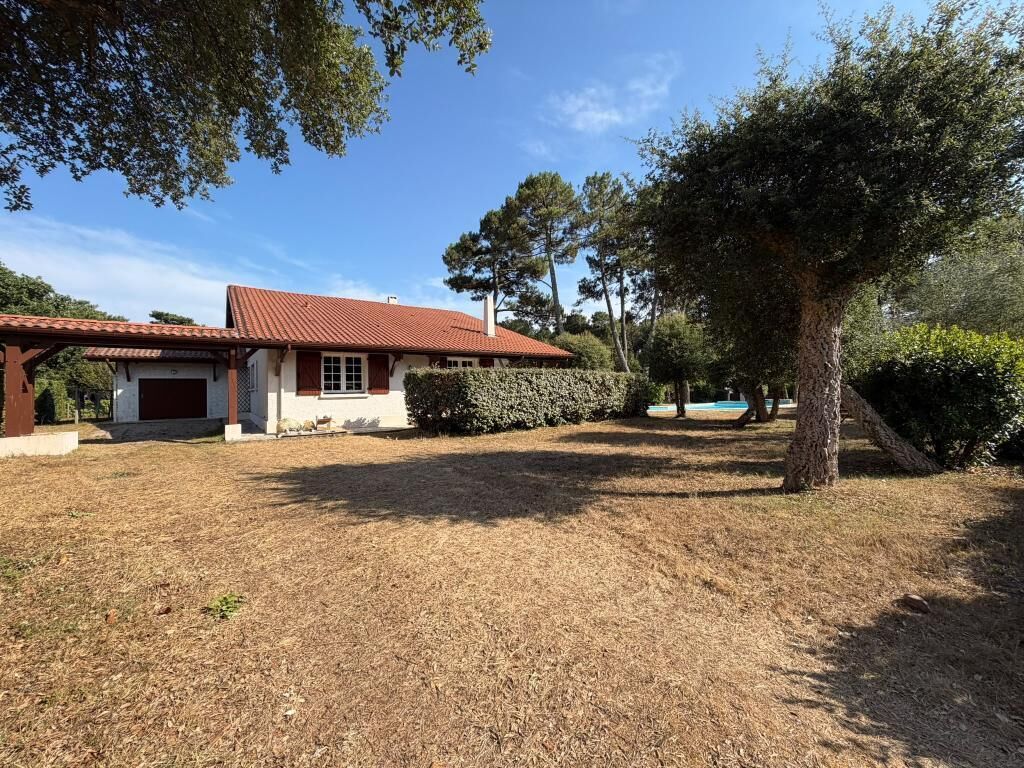 Une maison avec un toit rouge, une véranda et une pelouse bien entretenue.