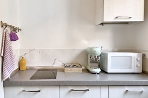 A kitchen with a microwave, a coffee maker, and a cutting board on the counter. - URNEST Abbadia - one-bedroom apartment in the city centre (Bologna)