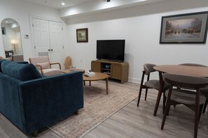 A living room with a sofa, chairs, a coffee table, a TV, and a dining table.