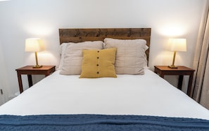 A bed with a wooden headboard, two bedside lamps, and a blue throw blanket. - A stylish retreat in Mount Pleasant, one of DC's most walkable neighborhoods. Two bedrooms plus a sofa bed sleep six, with two full baths - plus the city's rarest luxury: your own private off-street parking. Walk to Metro, cafes & Zoo. (Washington)