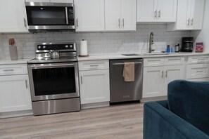 A modern kitchen with stainless steel appliances, white cabinetry, and a blue chair. - A stylish retreat in Mount Pleasant, one of DC's most walkable neighborhoods. Two bedrooms plus a sofa bed sleep six, with two full baths - plus the city's rarest luxury: your own private off-street parking. Walk to Metro, cafes & Zoo. (Washington)