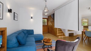 A modern living room with a blue sectional sofa, a wooden coffee table, and a staircase leading to an upper level. - Vacation home for 6 guests with private pool and garden. (Cagnes-sur-Mer)