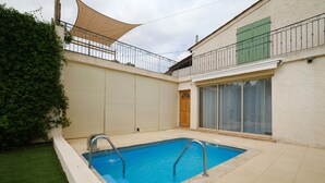 A rectangular swimming pool with a metal ladder, surrounded by a tiled patio. - Vacation home for 6 guests with private pool and garden. (Cagnes-sur-Mer)