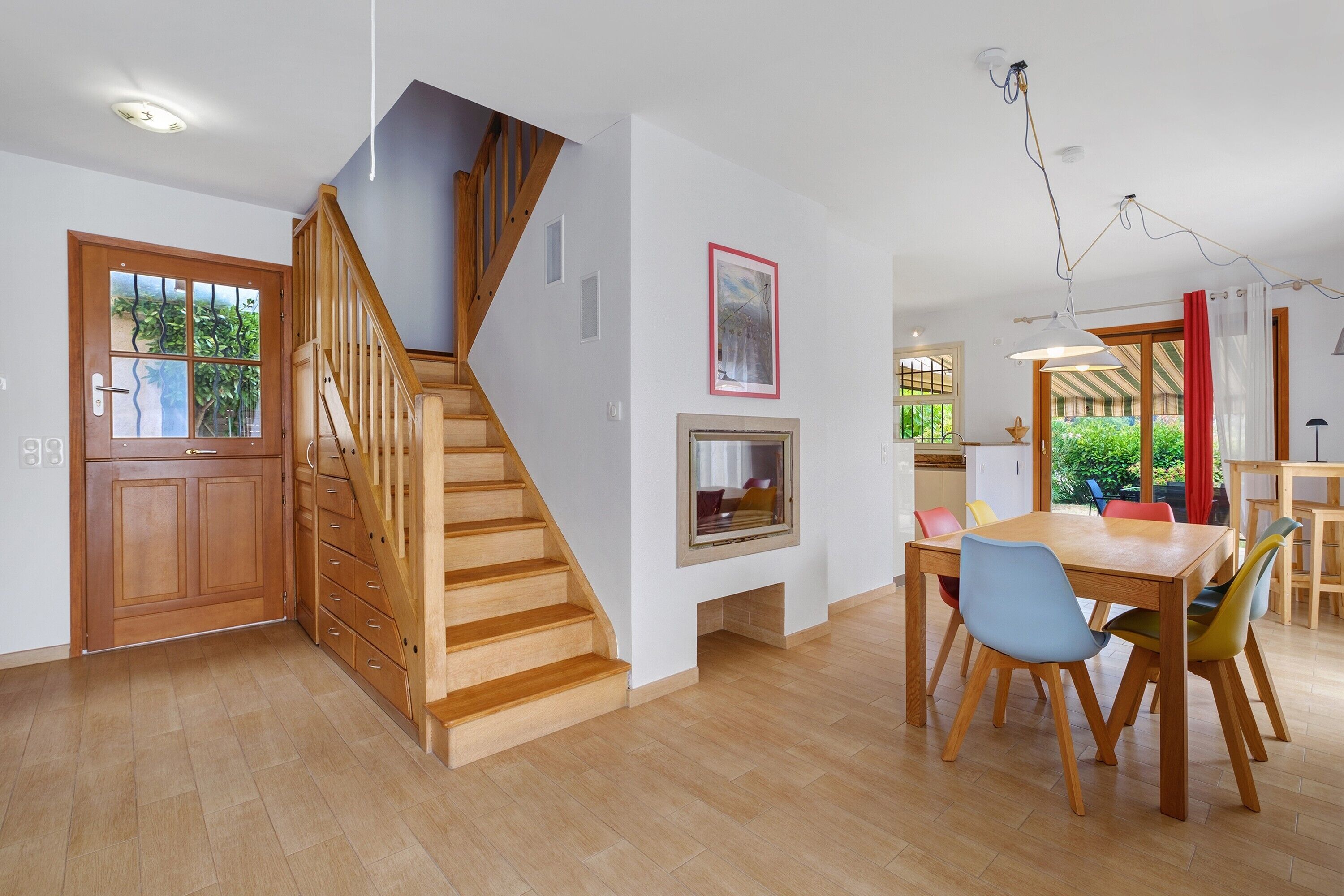A modern interior with a wooden staircase, a dining area, and a kitchen.