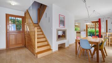 A modern interior with a wooden staircase, a dining area, and a kitchen.