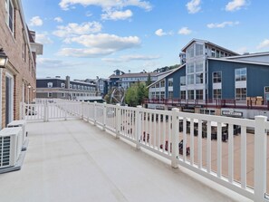A balcony with a white fence, air conditioning units, and a view of a building with a sign reading 'Park City Legacy Lodge Bar & Grill'. - Resort Center 5051 | Ski-In/Ski-Out | Mountain Views | Pool & Hot Tub Access (Park City)